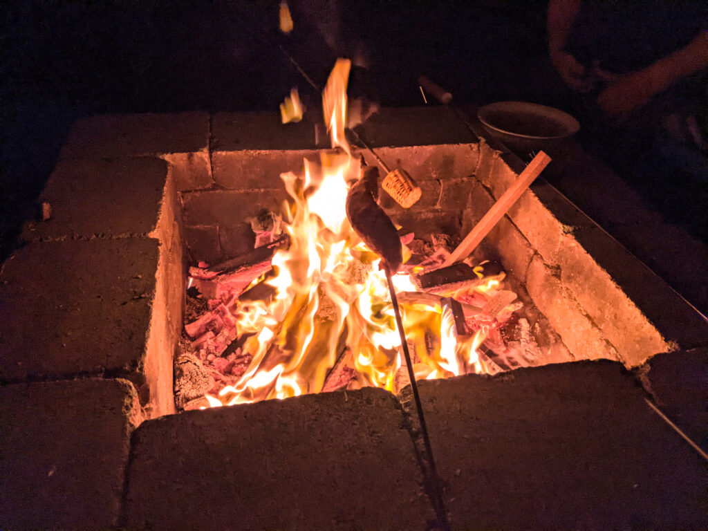 Stockbrot und Mais über dem Feuer